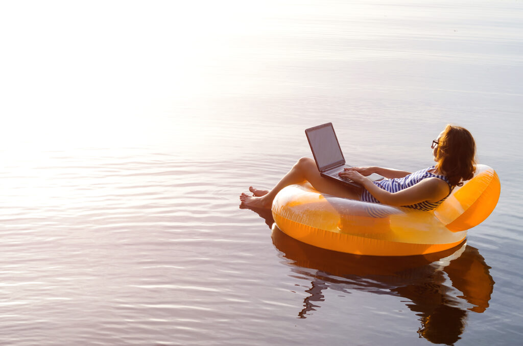 Woman working on a laptop in an inflatable ring in the water